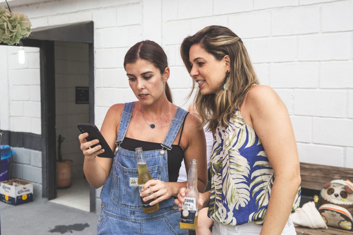 mulheres tomando cerveja e olhando para o celular