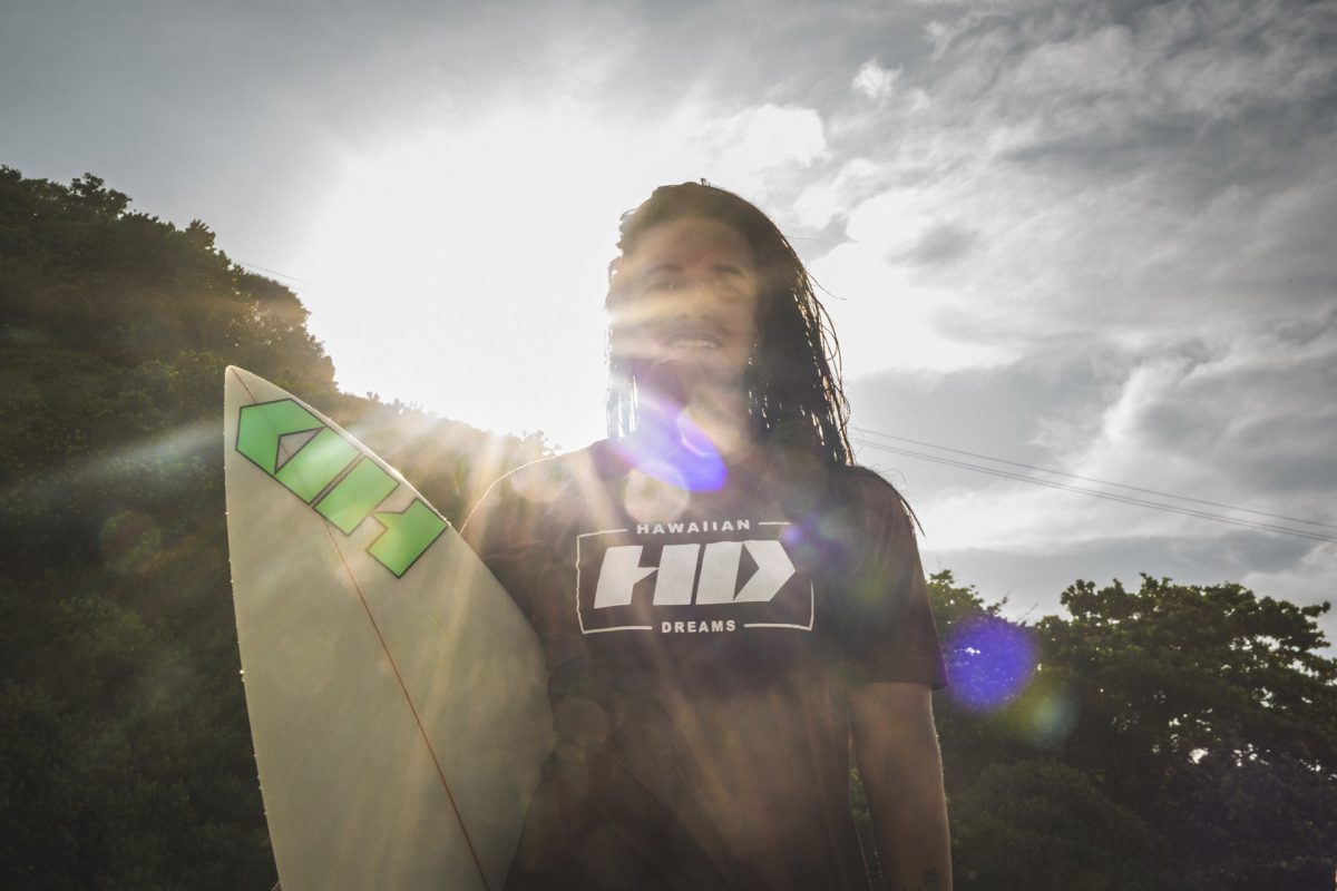 Surfista Julia Santos segurando prancha de surf com luz do sol